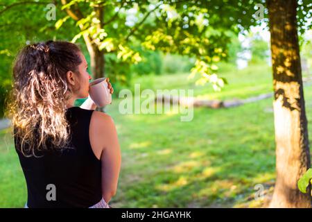 Sommer Land Landschaft Haus Veranda mit jungen Frau zurück sitzen auf Stufen vor oder Hinterhof Morgen Hütte trinken Kaffee oder Tee von mu Stockfoto