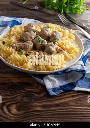 Fleischbällchen mit Sahnesauce und Pasta auf einem Teller Stockfoto