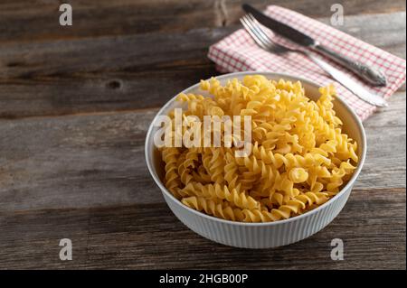 Fusilli rohe und ungekochte italienische Pasta in einer rustikalen Schüssel isoliert auf Holztisch von oben mit Kopieplatz Stockfoto