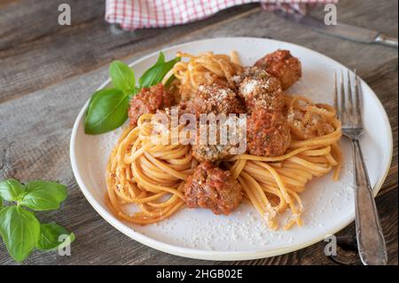 Traditionelles italienisches Gericht mit Spaghetti und Fleischbällchen. Serviert mit einer köstlichen Tomatensauce auf einem Teller auf einem Holztisch Stockfoto