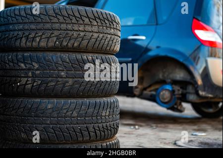 Winterreifen neben dem Auto im Radservice, saisonales Reifenwechselkonzept, Nahaufnahme Stockfoto