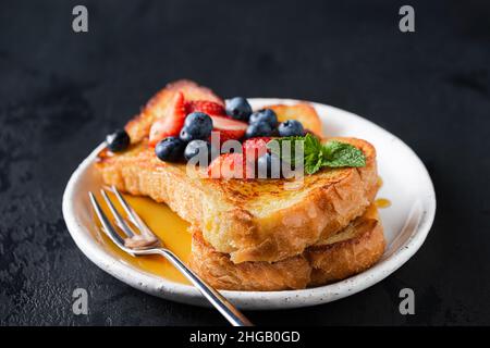 French Toast mit Beeren und Honig auf schwarzem Hintergrund Stockfoto