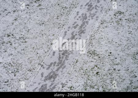 Instandhaltung von Straßen und Gehwegen im Winter. Leichter schneebedeckter Bürgersteig und menschliche Fußabdrücke auf Fußgängerweg. Luftaufnahme Stockfoto