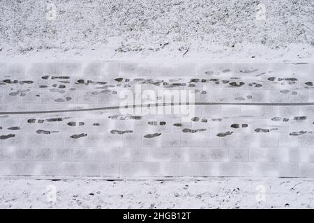 Instandhaltung von Straßen und Gehwegen im Winter. Leichter schneebedeckter Bürgersteig und menschliche Fußabdrücke auf Fußgängerweg. Luftaufnahme Stockfoto