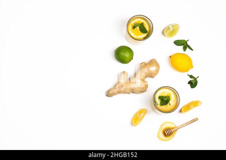 Tee, Ingwerwurzel, Honig, Zitronenscheiben und grüne frische Minze lagen isoliert auf weißem Hintergrund. Zusammensetzung des Konzepts „Food Balance and Detox“. Stockfoto