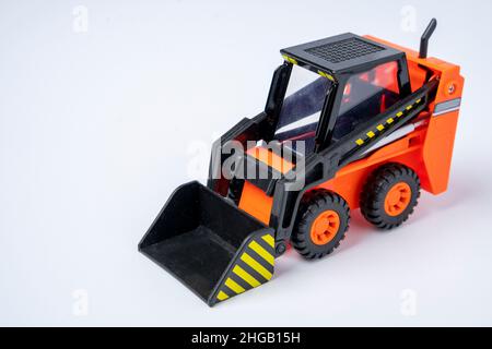 Orange Toy Loader auf weißem Hintergrund, Mini-Loader, Spielzeug-Industrieauto, Kunststoff-Frontlader. Stockfoto