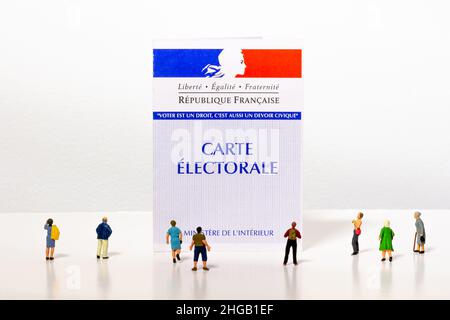 Kleine Bürgerfiguren, die sich einen französischen Wahlausweis angucken. Jeder Wähler erhält eine Wählerkarte, mit der er bei Wahlen in Frankreich wählen kann Stockfoto