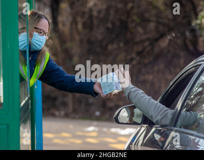 Langhorne, Usa. 19th Januar 2022. Donna Thompson übergibt einem Fahrer die Kits, während Hunderte von Einwohnern von Bucks County auf dem Parkplatz auf einer schnellen Fahrt durch die Schlange warteten, um kostenlose COVID-19 Rapid-Testkits zu erhalten Mittwoch, 19. Januar 2022, am Sesame Place in Langhorne, Pennsylvania. Es wurde erwartet, dass die Notfallverwaltungsbehörde und das Gesundheitsministerium des Bezirks in den nächsten Wochen von 10 bis 6 Uhr jeden Verteilungstag 300.000 Testkits ausliefern werden, solange der Vorrat reicht. Kredit: William Thomas Cain/Alamy Live Nachrichten Stockfoto