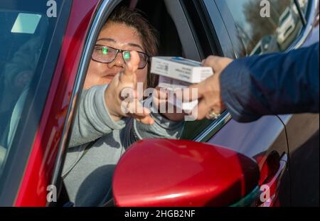 Langhorne, Usa. 19th Januar 2022. Eine Frau greift nach 4 Testkits, als Hunderte von Einwohnern von Bucks County auf einem schnellen Weg durch die Schlange auf dem Parkplatz warteten, um kostenlose COVID-19 Rapid-Testkits zu erhalten Mittwoch, 19. Januar 2022, am Sesame Place in Langhorne, Pennsylvania. Es wurde erwartet, dass die Notfallverwaltungsbehörde und das Gesundheitsministerium des Bezirks in den nächsten Wochen von 10 bis 6 Uhr jeden Verteilungstag 300.000 Testkits ausliefern werden, solange der Vorrat reicht. Kredit: William Thomas Cain/Alamy Live Nachrichten Stockfoto