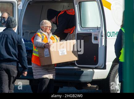 Langhorne, Usa. 19th Januar 2022. Mitarbeiter des Notfallmanagements von Bucks County liefern weitere Tests zur Verteilung, da Hunderte von Einwohnern von Bucks County in einer schnellen Fahrt durch die Schlange auf dem Parkplatz warteten, um kostenlose COVID-19 Rapid-Testkits zu erhalten Mittwoch, 19. Januar 2022 am Sesame Place in Langhorne, Pennsylvania. Es wurde erwartet, dass die Notfallverwaltungsbehörde und das Gesundheitsministerium des Bezirks in den nächsten Wochen von 10 bis 6 Uhr jeden Verteilungstag 300.000 Testkits ausliefern werden, solange der Vorrat reicht. Kredit: William Thomas Cain/Alamy Live Nachrichten Stockfoto