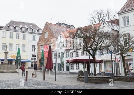 Flensburg, Deutschland - 9. Februar 2017: Blick auf den Nordermarkt, Stadtplatz mit Neptunbrunnen, gewöhnliche Menschen gehen die Straße entlang Stockfoto