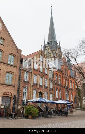 Flensburg, Deutschland - 9. Februar 2017: Blick auf die Straße mit der Nikolaikirche oder der St. Nikolas-Kirche von Flensburg, normale Menschen gehen in der Nähe Stockfoto