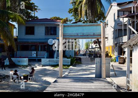 Ein Schokoladengeschäft in San Pedro, Belize, am Strand mit belizischen Händlern, die ihr Holzhandwerk verkaufen, und eine Straße mit geparkten Golfwagen. Stockfoto