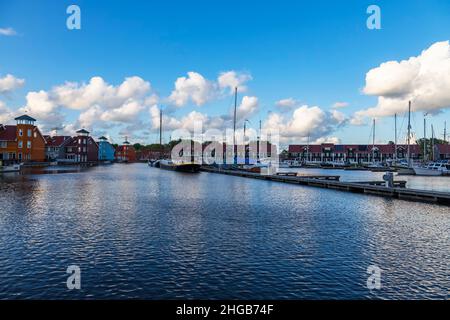 Groningen in Holland bei Sonnenaufgang. Am blauen Himmel sind weiße Wolken über bunten Häusern. Stockfoto