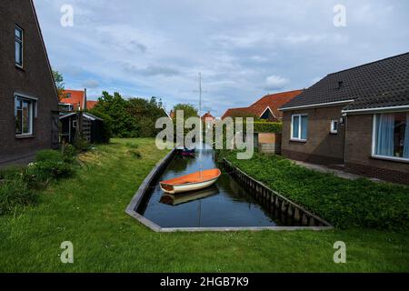 Wasserkanal zwischen Häusern in Hindeloopen in Holland. Es gibt ein Boot auf dem Wasser. Stockfoto