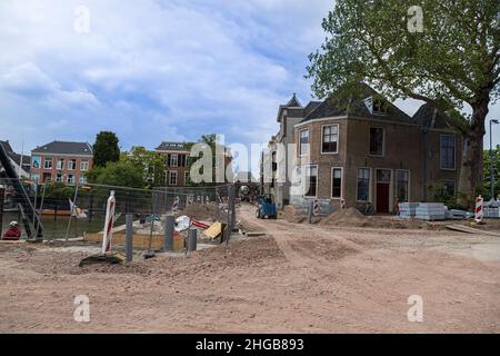 Kippen Sie Häuser in einer Straße in Dordrecht, Holland. Die Straße wird repariert und es gibt Baumaschinen darauf. Stockfoto