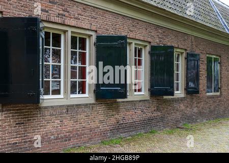 Große Fenster auf das Haus mit Backsteinmauer und Fensterläden. Es ist eine Kirche in Dordrecht, Holland. Stockfoto