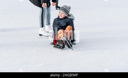 Weich, selektive Fokus.das Kind steht auf, fiel auf Schlittschuhe, kniet, spielen Spaß Rest am Wochenende erste Schritte Kind skates.Mom mit Baby Junge 6 Jahre alt, lernen Stockfoto