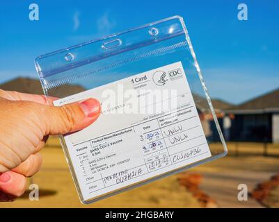 Oklahoma, 16 2021. DEZEMBER - Nahaufnahme einer Hand mit einer Impfkarte und drei gestempelten Dosen Stockfoto