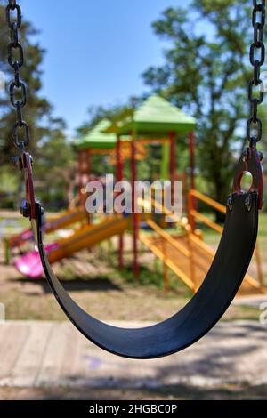 Nahaufnahme leere Schaukel auf dem Spielplatz während der Quarantäne in Argentinien. Selektiver Fokus. Hintergrund verwischen. Vertikal Stockfoto