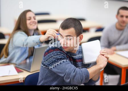 Die Schüler necken sich gegenseitig und haben Spaß während des Unterrichts in einem modernen Klassenzimmer Stockfoto