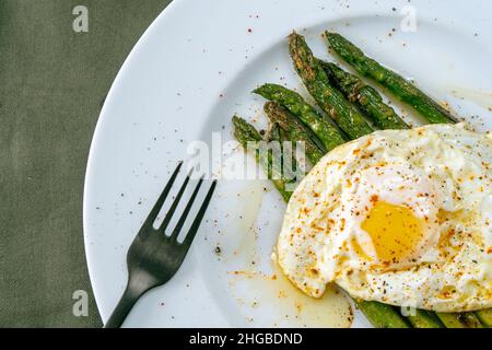 Ein exquisiter gekochter Spargel, zubereitet mit einem Spiegelei, gewürzt und gewürzt. Natürliche Küche, Gourmet. Stockfoto