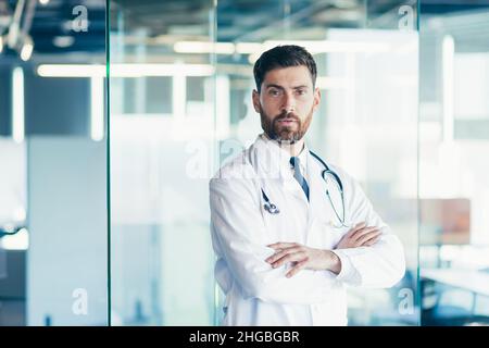 Erfolgreicher männlicher Arzt lächelt und schaut in der Klinik auf die Kamera Stockfoto