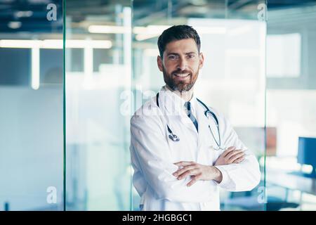 Erfolgreicher männlicher Arzt lächelt und schaut in der Klinik auf die Kamera Stockfoto