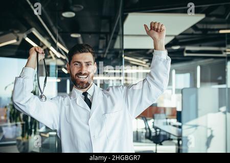 Glücklicher und erfolgreicher Arzt in einem weißen medizinischen Kleid, tanzend vor Freude, zufrieden mit dem Ergebnis seiner Arbeit, schnelle Genesung des Patienten, in einem Modus Stockfoto