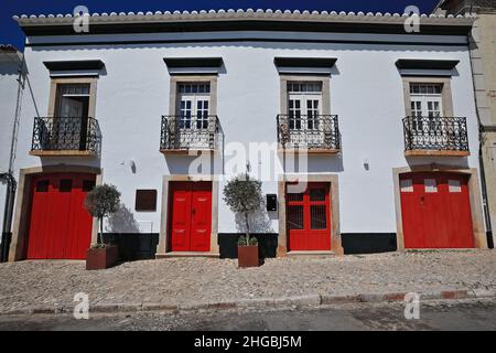 Weiß getünchte Fassade-landestypische Stadthaus-rote Türen-vier Balkone mit schmiedeeisernen Geländern. Tavira-Portugal-069 Stockfoto