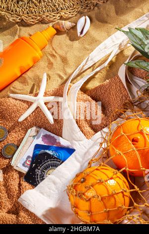 Konzept eines Strandurlaubs mit Sand, Blick von oben. Sandhintergrund mit Kopierplatz für Text, selektiver Fokus. Urlaubskonzept mit Obst und Accessoires Stockfoto