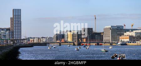 Die Mautbrücke von Tom Clarke über den Liffey, Gebäude im Finanzdistrikt entlang der Kais und das höchste Gebäude im „Capital Dock“ der Stadt. Dublin, Irland Stockfoto