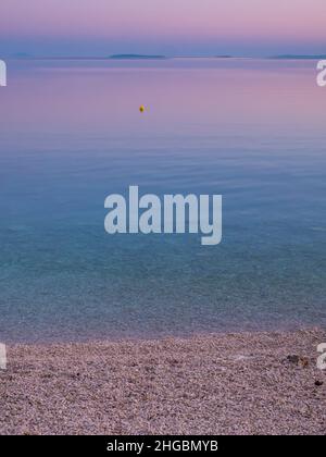 Strand und Meerblick auf der Insel Vir, Kroatien am frühen Morgen. Schöner lila und rosa Himmel und Adria. Stockfoto