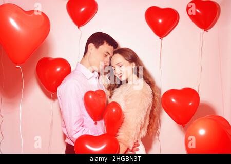 Mann mit seinem lieblichen Liebsten Mädchen Kuss auf Lover Valentinstag. Valentinspaar. Paar küssen und umarmen. Auf dem Hintergrund rote Luftballons Herzen. Love Konz Stockfoto