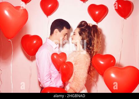 Mann mit seinem lieblichen Liebsten Mädchen Kuss auf Lover Valentinstag. Valentinspaar. Paar küssen und umarmen. Auf dem Hintergrund rote Luftballons Herzen. Love Konz Stockfoto