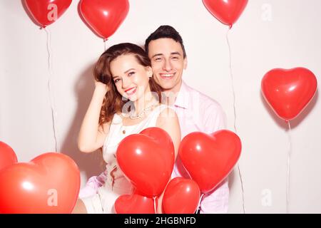 Mann mit seinem lieblichen Liebsten Mädchen tanzen und haben Spaß am Valentinstag von Lover. Valentine Paarty. Hintergrund rote Ballons Herzen. Liebeskonzept. Stockfoto