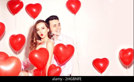 Mann mit seinem lieblichen Liebsten Mädchen tanzen und haben Spaß am Valentinstag von Lover. Valentine Paarty. Hintergrund rote Ballons Herzen. Liebeskonzept. Stockfoto