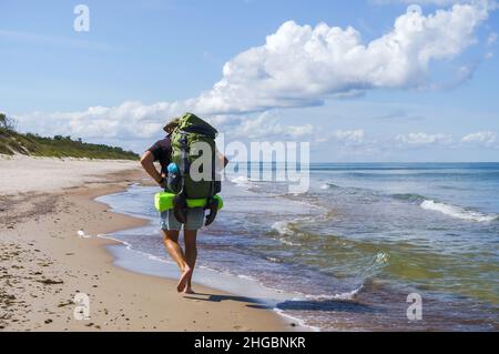 Region Königsberg, Ostsee, Russland, 5. August 2021. Eine Wanderung entlang der Küste. Ein Mann mit einem großen Rucksack. Ein Tourist spaziert entlang der Küste Stockfoto