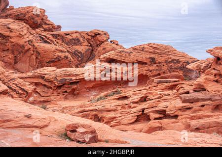 Overton, Nevada, USA - 24. Februar 2010: Valley of Fire. Abfolge von verschiedenen Stilen von rissigen, gesäumten und löcherten roten Felsen unter dicken grauen Wolken Stockfoto