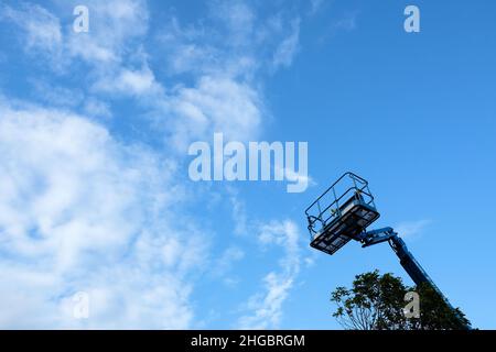 Korb am Ende eines Genie-Teleskopauslegers mit blauem Himmel und wispigen Cirrus-Wolken im Hintergrund; Industriebau, Service-Ausrüstung. Stockfoto