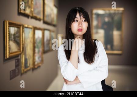 Chinesische Frau in der Nähe der Bildersammlung im Museum Stockfoto