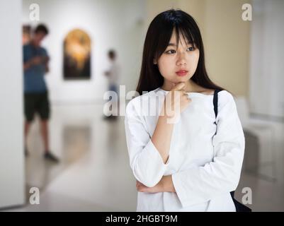 Chinesische junge Frau in der Nähe der Bildersammlung im Museum Stockfoto