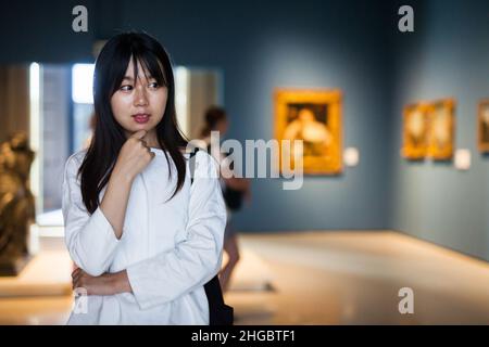 Chinesische junge Frau in der Nähe der Bildersammlung im Museum Stockfoto