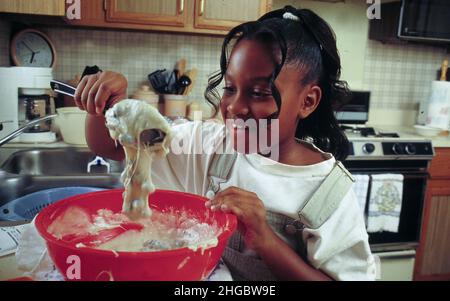 Austin, Texas USA 1997: Acht Jahre altes Mädchen, das zu Hause Heidelbeer-Muffins kocht MR EU-0208 ©Bob Daemmrich Stockfoto