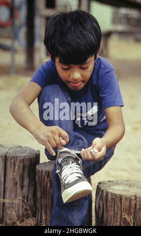 Austin, Texas USA: Kindergartenkind, das nach dem Stint auf dem Spielplatz Schuhe schnürt. HERR ©1991 Bob Daemmrich Stockfoto