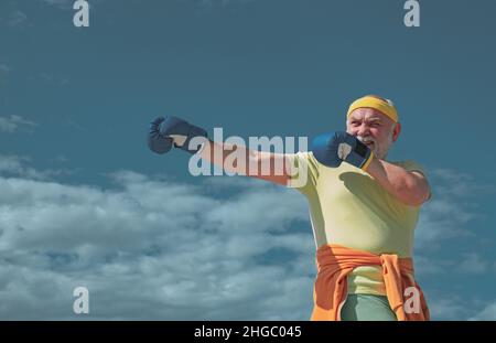Schöner älterer Mann, der Boxkick übt. Älterer sportlicher Mann im Boxsport, der Übungen mit Boxhandschuhen macht. Ich liebe Boxen. Stockfoto
