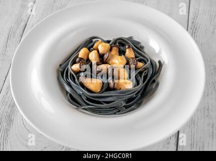 Tintenfisch Tinte Linguine Pasta mit Babypilzen Stockfoto