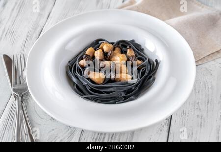 Tintenfisch Tinte Linguine Pasta mit Babypilzen Stockfoto