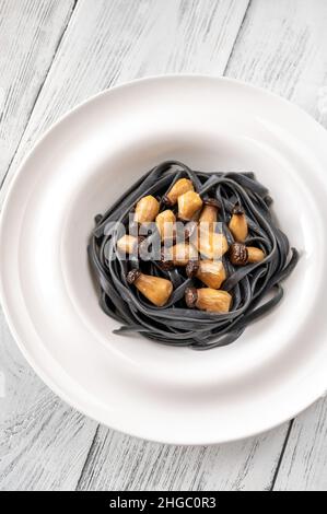 Tintenfisch Tinte Linguine Pasta mit Babypilzen Stockfoto