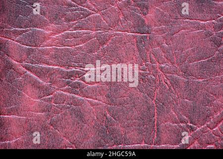 Fragment aus echtem Leder mit Falten, künstlich in dunklem Burgund und getöntem Schwarz gefärbt. Hintergrund, Muster, Textur. Stockfoto